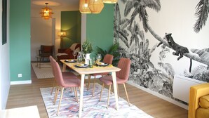 A dining area with a table set for four, surrounded by chairs, and a mural of a jungle scene on the wall.