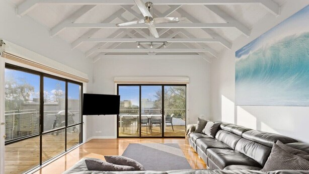A spacious living room with a large window, a ceiling fan, and a view of the outdoors. - Sea La Vie, King Bed, Sleeps 7 (Cowes)