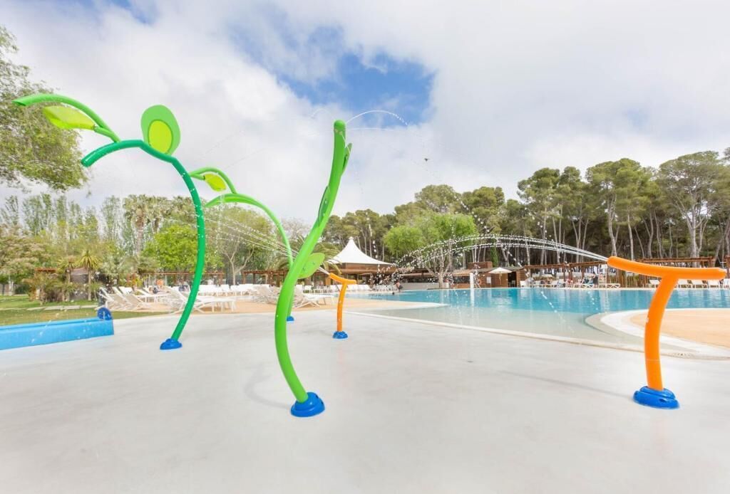 A water park with green and orange water features, a pool, and a covered seating area.