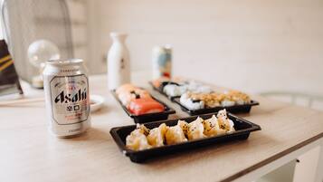 Una mesa con una lata de cerveza Asahi, sushi y una pieza decorativa de cerámica.