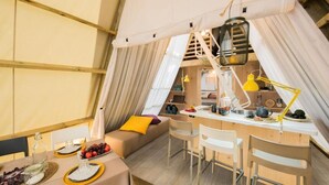 A cozy, well-lit tent-style room with a dining area, a sofa with cushions, and a small kitchen setup. - Tamarit Beach Resort (Tarragona)