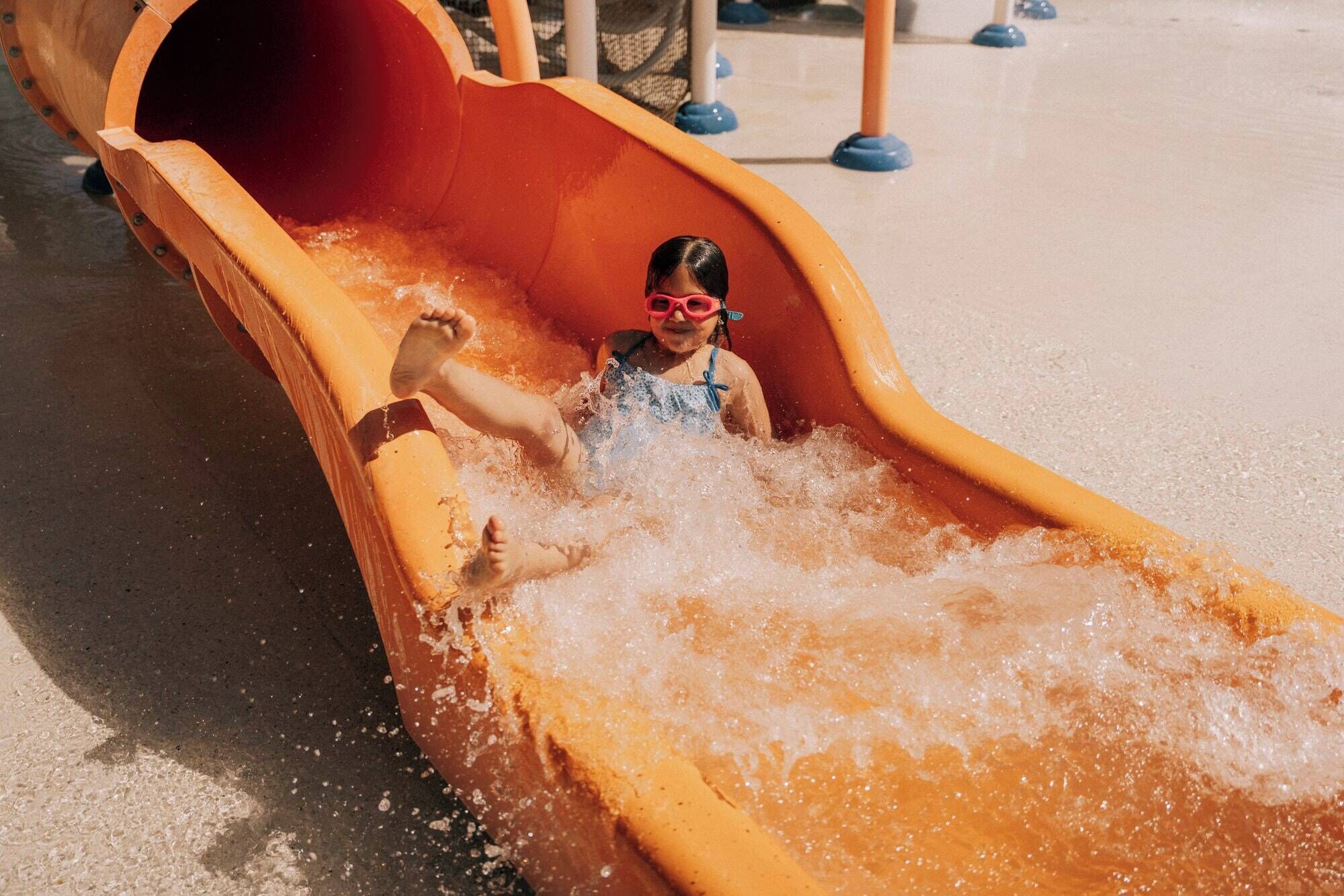 Un niño resbalando por un tobogán acuático en un parque acuático.