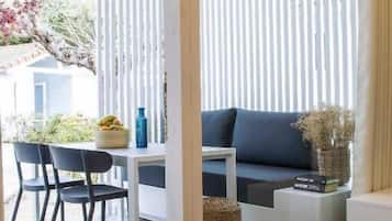 Un espacio moderno para la vida con un sofá, una mesa de comedor con sillas y un amplio ventanal con persianas verticales.