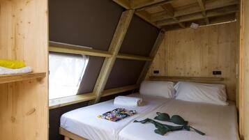 Un dormitorio pequeño de madera estilo ático con una cama individual, una ventana y una repisa con un objeto amarillo.