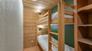 Une chambre avec des lits superposés, des murs en bois et un mur d’accent de couleur verte.
