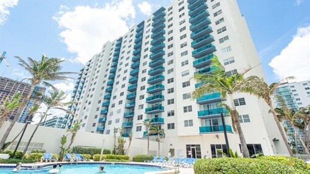 A high-rise hotel with a swimming pool, palm trees, and a clear blue sky. - SIAN private apartment (Hollywood)
