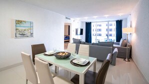A modern living room with a sofa, a dining table with chairs, and a TV mounted on the wall. - SIAN private apartment (Hollywood)