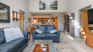 Una sala moderna con un sofá azul, una mesita de centro y una cocina al fondo.