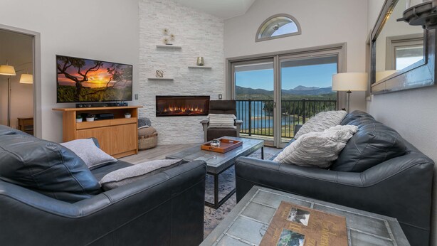 Una sala de estar moderna con chimenea, sofás de cuero y un amplio ventanal con vistas panorámicas.