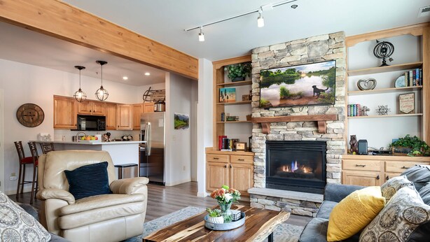 A modern living room with a fireplace, comfortable seating, and a kitchen in the background. - Fourth & Main Condo: Heart of Frisco (Frisco)