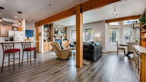 A spacious living area with a wooden floor, a fireplace, and a dining area with a table and chairs. - Fourth & Main Condo: Heart of Frisco (Frisco)