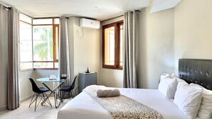 Una habitación de hotel con cama, escritorio, sillas y ventana con cortinas.