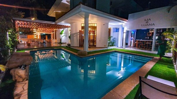 Una casa moderna con piscina, un porche cubierto y una zona de bar.