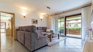 Een moderne woonkamer met een modulaire bank, een salontafel en een schuifpui naar een buitenruimte.