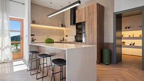 Una cocina moderna con una isla central, taburetes de bar y electrodomésticos integrados.