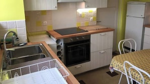 Een kleine keuken met een spoelbak, fornuis en kastjes.