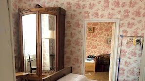 Een slaapkamer met een houten bed, een houten kast en een bureau.