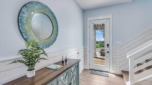 A hallway with a wooden floor, a white door, and a staircase. - Nauti Capitan: Where the ocean’s call is always heard, and adventure awaits. (Port Aransas)