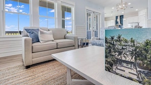 A modern living room with a beige sofa, a coffee table, and a magazine titled "This must be Paradise" on the table. - Nauti Capitan: Where the ocean’s call is always heard, and adventure awaits. (Port Aransas)