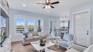 A spacious living room with a sofa, chairs, a coffee table, and a ceiling fan. - Nauti Capitan: Where the ocean’s call is always heard, and adventure awaits. (Port Aransas)