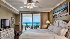 Una habitación de hotel con una cama, televisión, una silla, escritorio y vista al océano.