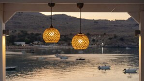 A view from a covered area overlooking a body of water with boats, under a structure with hanging lamps.