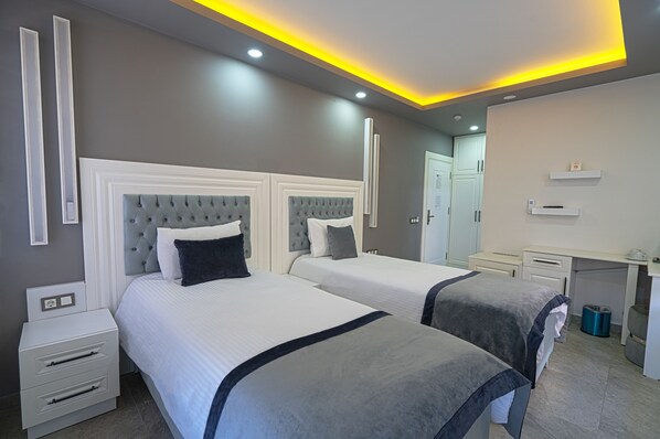 Una habitación de hotel con dos camas, un escritorio y un espejo.