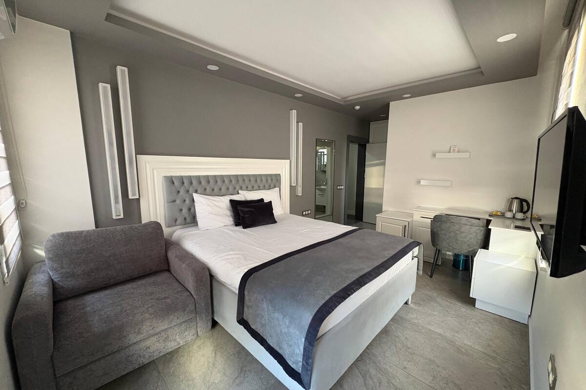 Una camera d'albergo moderna con un letto grande, una scrivania e una sedia.