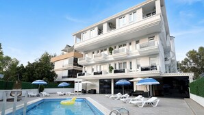 Un hôtel doté d’une piscine, de chaises longues et de parasols.