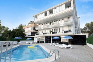 Un hotel con piscina, tumbonas y sombrillas.
