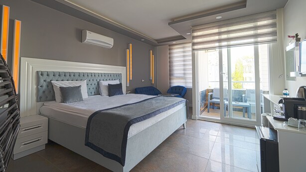 Une chambre d’hôtel moderne dotée d’un grand lit, d’un bureau et d’un balcon avec coin salon extérieur.