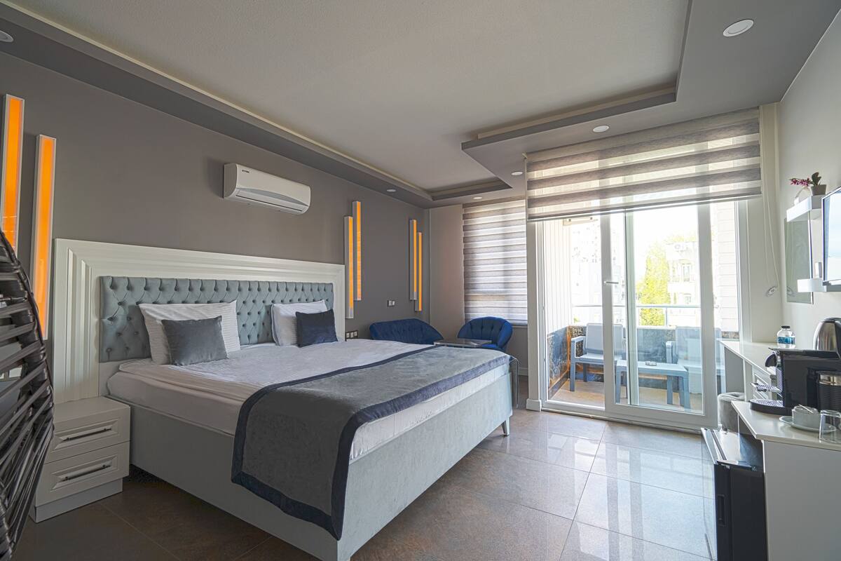 Una camera d'albergo moderna con un letto grande, una scrivania e un balcone con posti a sedere.