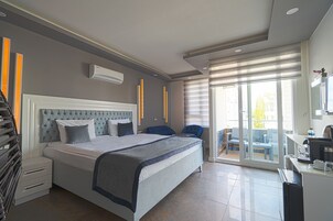 Una habitación de hotel moderna con una cama grande, un escritorio y un balcón con mobiliario exterior.