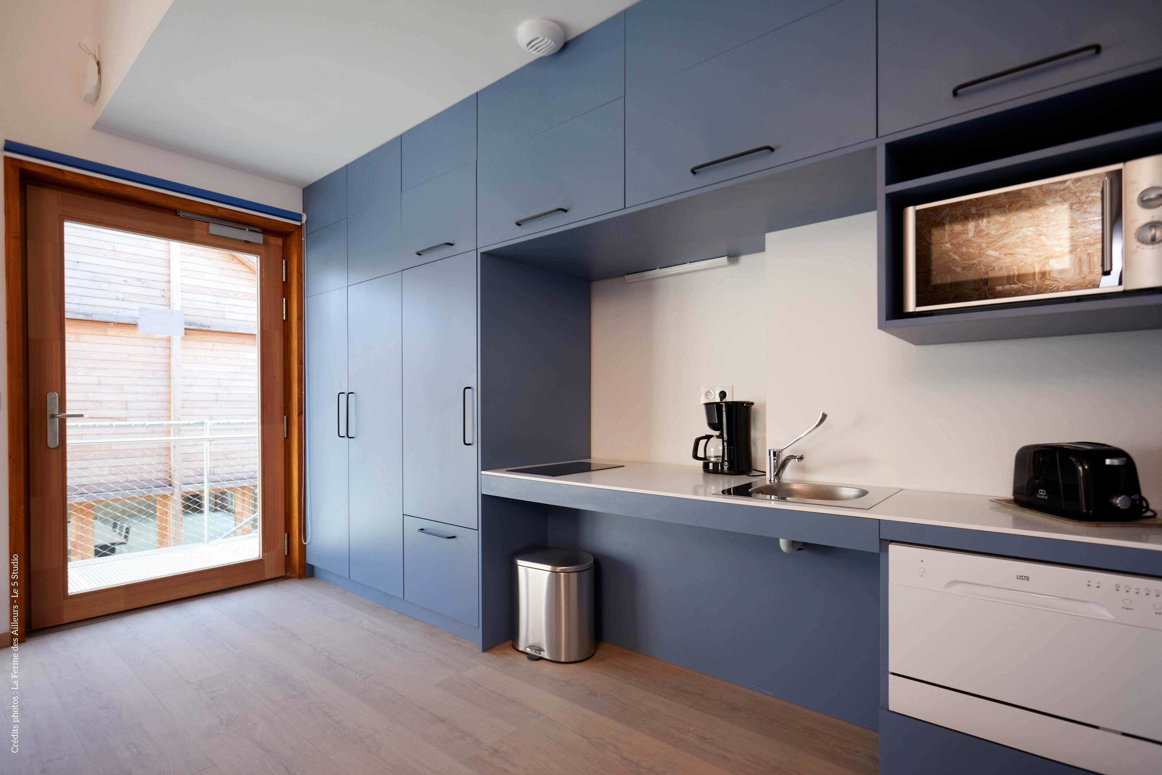 A modern kitchen with grey cabinets, a stainless steel sink, a coffee maker, and a dishwasher.
