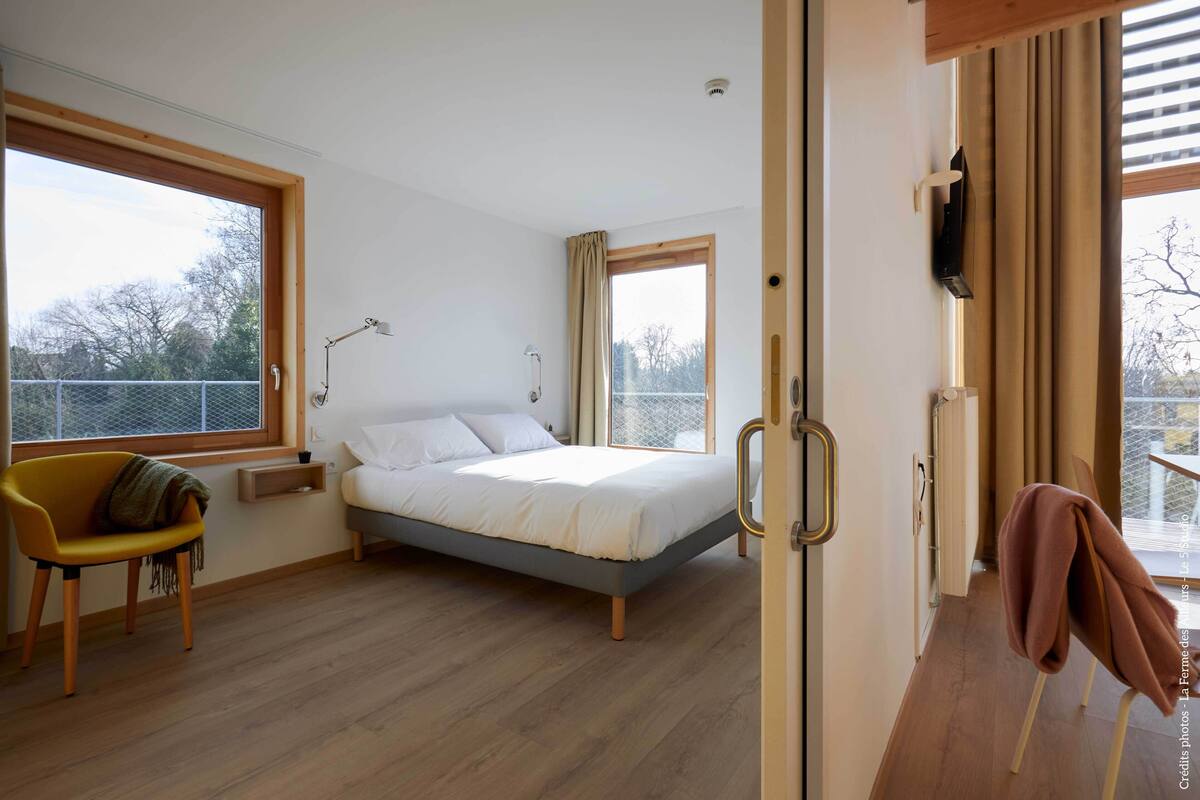 Um quarto com uma cama, uma cadeira, uma janela e uma porta.