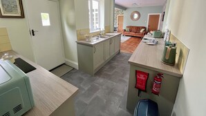 Een moderne keuken met een centraal eiland, een eethoek met een houten tafel, en een woonkamer met een bruine bank.