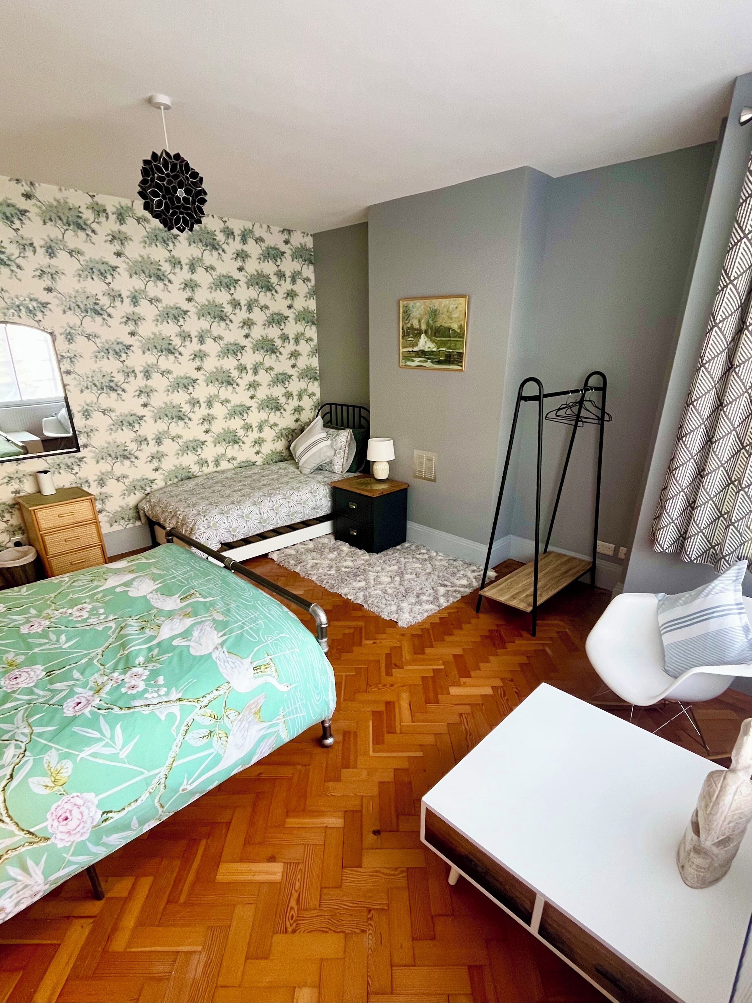 A bedroom with a bed, bedside table, lamp, and a chair.