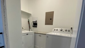 Une cuisine compacte équipée d’un lave-linge et d’un sèche-linge, d’un plan de travail et d’un petit placard.