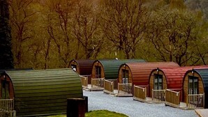 A row of small, arched-roof cabins with wooden railings, set in a wooded area.