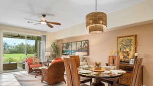 A dining area with a round table, wooden chairs, and a ceiling fan.