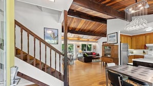 A spacious living area with a wooden staircase, a dining area with a modern table, and a kitchen with wooden cabinets and stainless steel appliances. - Moondance - Contemporary Riverfront Home (Monte Rio)