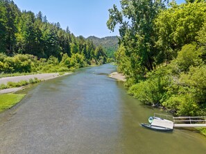 A river with a dock and a small boat. - Moondance - Contemporary Riverfront Home (Monte Rio)