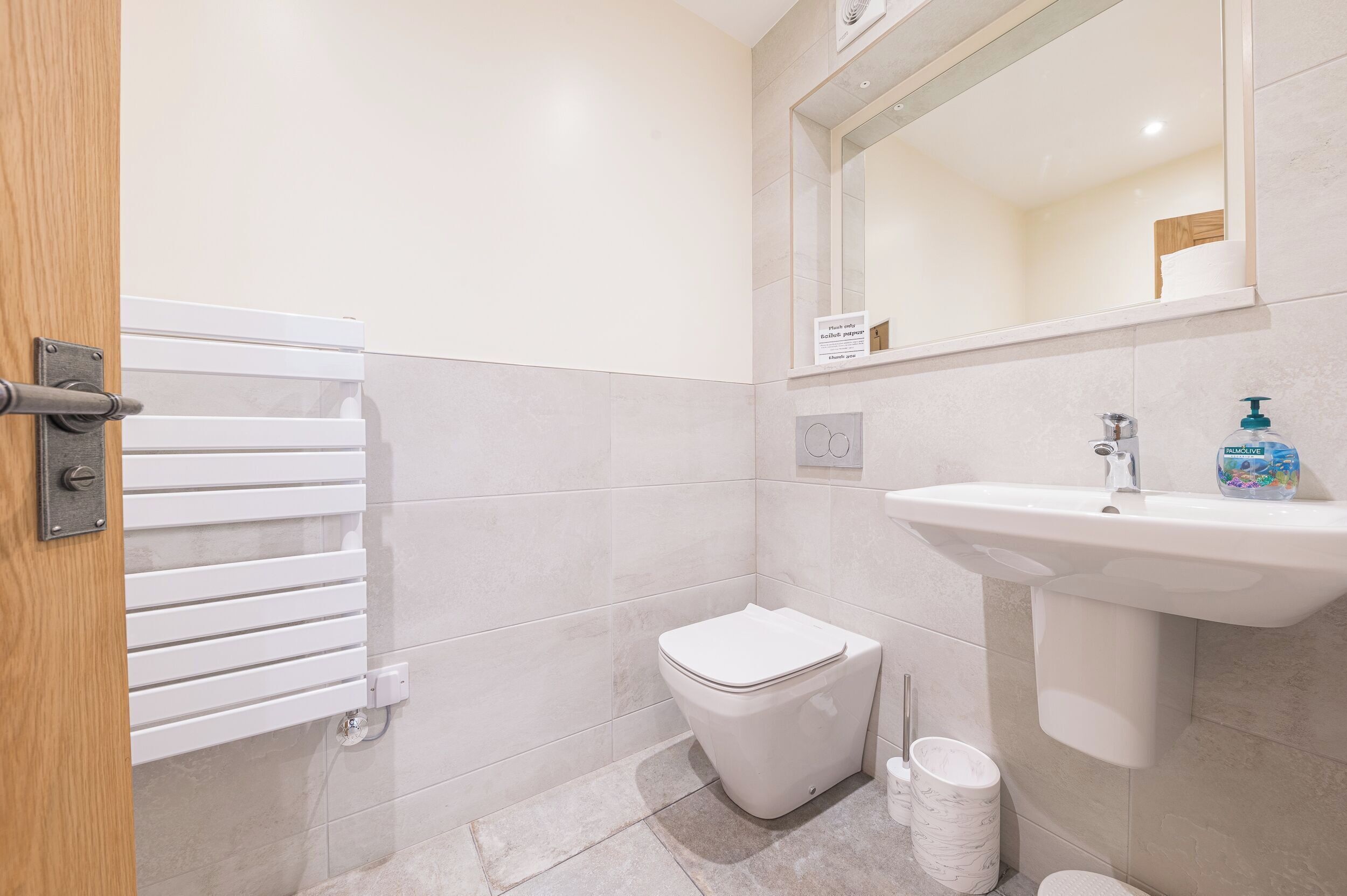 A bathroom with a white toilet, a sink with a soap dispenser, and a towel rack.