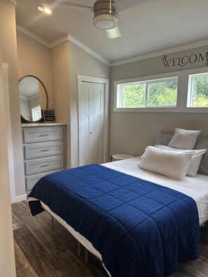 Ein Schlafzimmer mit Bett, Kommode, Spiegel, Fenster und einem 'WELCOME'-Schild.