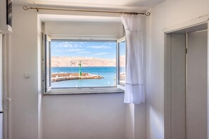 A room with a window overlooking a body of water and a distant landscape. - 1BR Seafront Apartment Sanja Karlobag (Karlobag)
