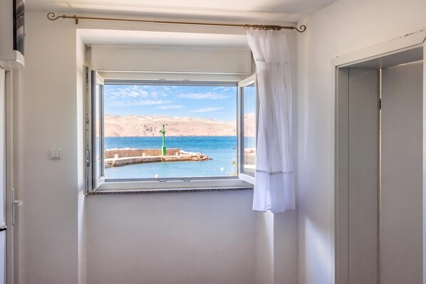 A room with a window overlooking a body of water and a distant landscape.