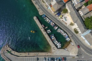 Vista aérea de una zona costera con un puerto deportivo, barcos y edificios a lo largo de la orilla.