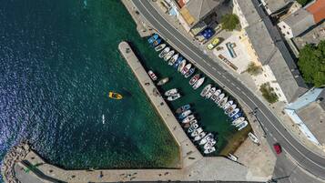 An aerial view of a coastal area with a marina, boats, and buildings along the shore.
