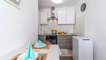 A compact kitchen with white cabinets, a built-in oven, and a white refrigerator.