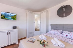 A bedroom with a bed, a TV, a wardrobe, and a magazine on the bed. - 1BR Seafront Apartment Sanja Karlobag (Karlobag)